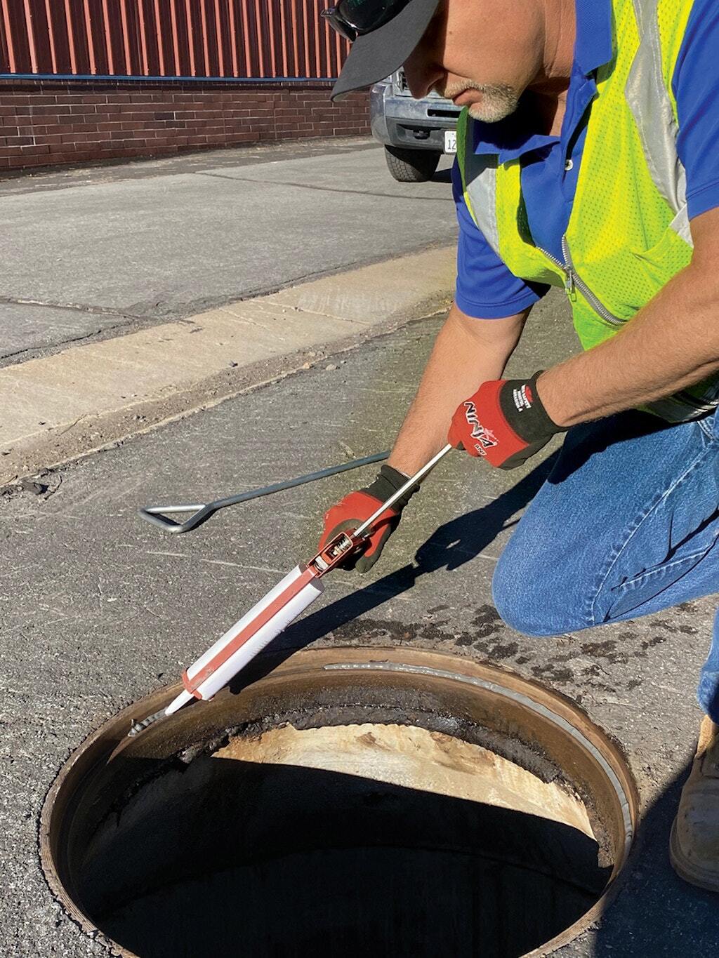 A worker with the Truckee Sanitary District uses a caulking gun to apply Hercules Shutout lubricant and sealant to a manhole lip.